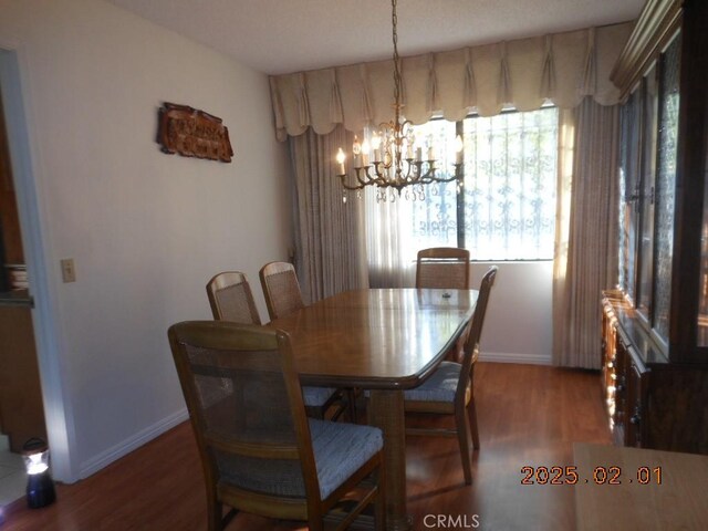 dining area with hardwood / wood-style flooring and an inviting chandelier