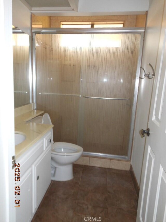 bathroom featuring vanity, tile patterned flooring, a shower with door, and toilet