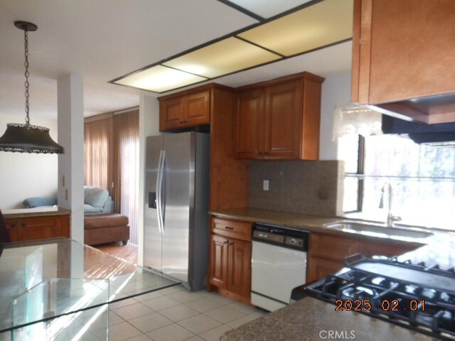 kitchen featuring sink, hanging light fixtures, stainless steel fridge, white dishwasher, and decorative backsplash