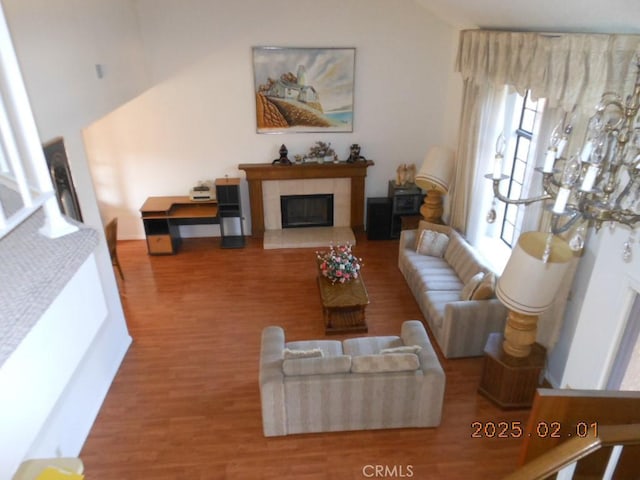 living room featuring lofted ceiling, wood-type flooring, and a tile fireplace