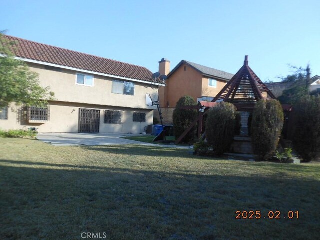 back of property featuring a lawn and a patio