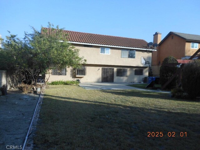 rear view of house featuring a yard and a patio