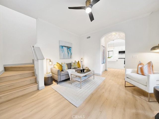 living room featuring ceiling fan, ornamental molding, and light wood-type flooring