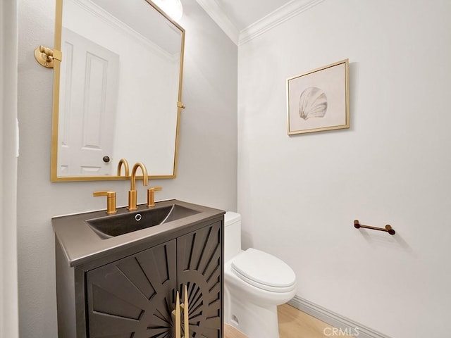half bathroom with wood finished floors, vanity, ornamental molding, and toilet