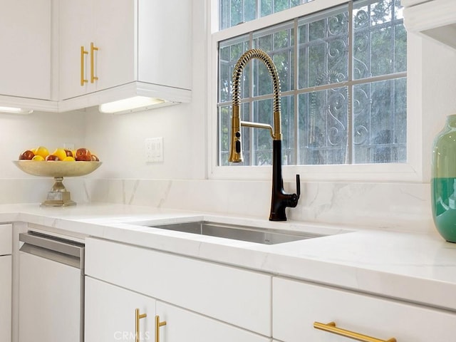 kitchen with white cabinetry, sink, and light stone counters