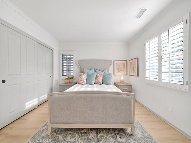 bedroom featuring multiple windows, ornamental molding, and light hardwood / wood-style flooring