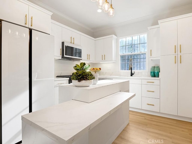 kitchen featuring sink, white cabinets, a center island, crown molding, and white appliances