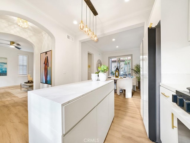 kitchen with white cabinetry, ceiling fan, light wood-type flooring, and decorative light fixtures