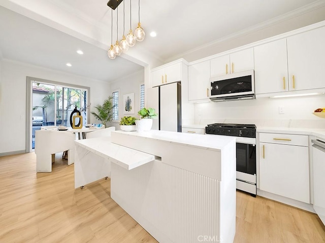 kitchen featuring fridge, a center island, range with gas stovetop, white cabinets, and decorative light fixtures