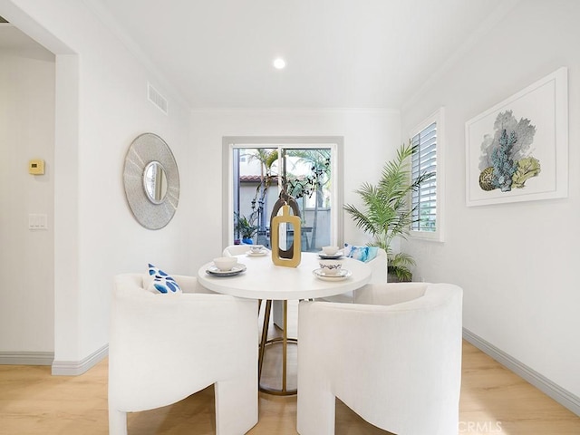 dining room featuring visible vents, light wood finished floors, baseboards, and ornamental molding