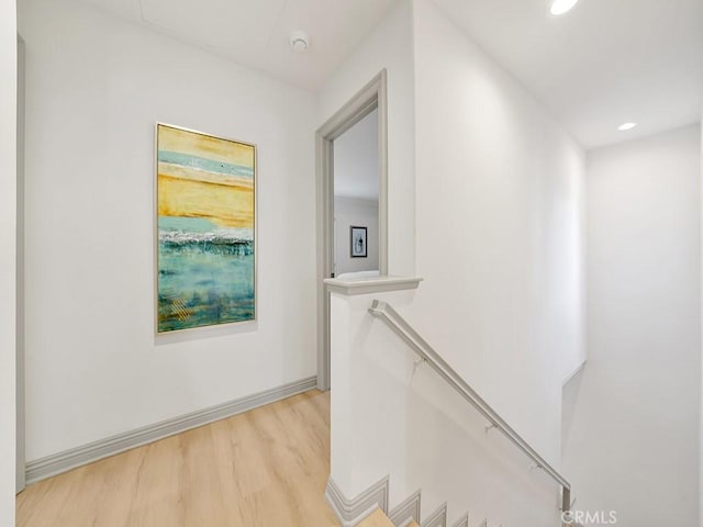 hall featuring recessed lighting, light wood-style floors, baseboards, and an upstairs landing