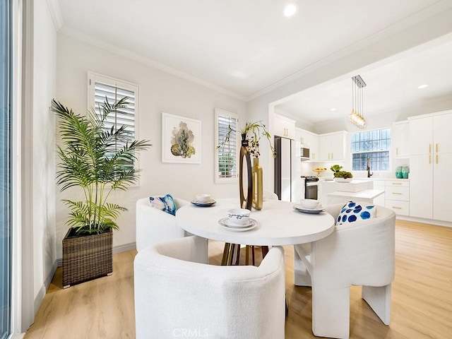 dining area featuring ornamental molding and light hardwood / wood-style flooring