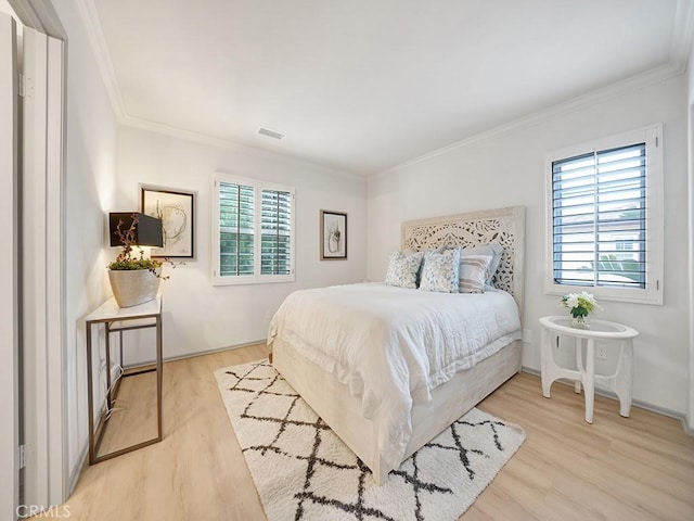 bedroom featuring multiple windows, crown molding, and light hardwood / wood-style floors