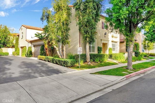 view of front of home featuring a garage, a tiled roof, driveway, and stucco siding