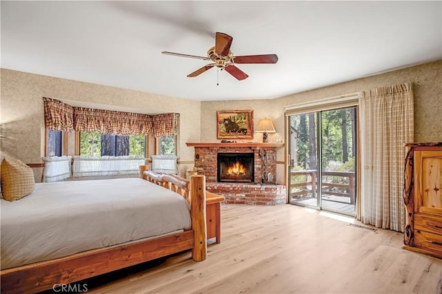 bedroom with light hardwood / wood-style flooring, a brick fireplace, multiple windows, and access to outside