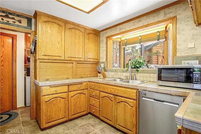 kitchen with stainless steel appliances, tile counters, washer / dryer, and sink