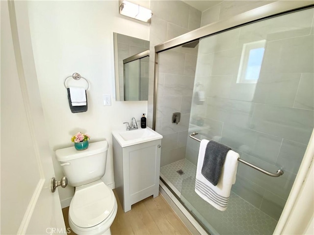 full bathroom with a stall shower, vanity, toilet, and wood finished floors