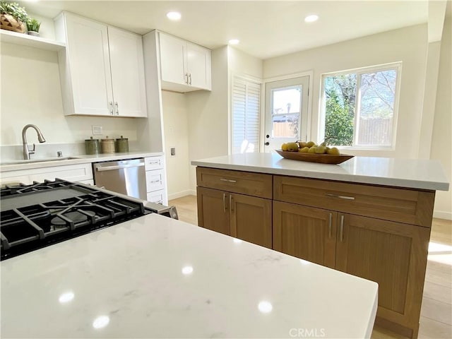 kitchen with a sink, white cabinets, stainless steel dishwasher, open shelves, and brown cabinetry