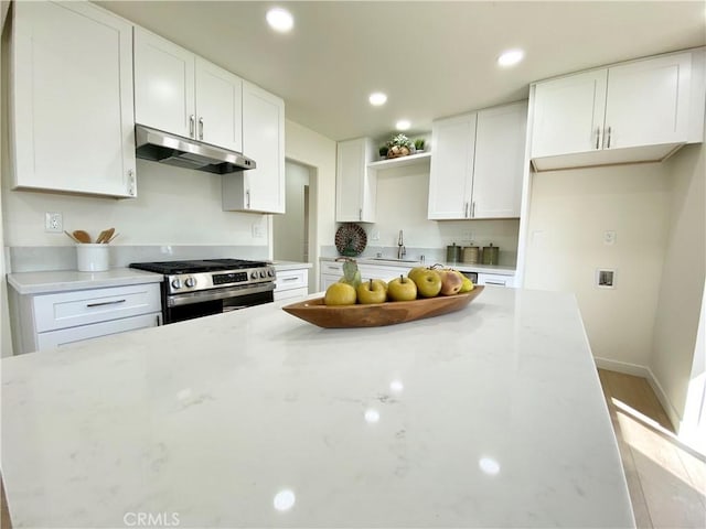 kitchen with white cabinets, under cabinet range hood, and gas range