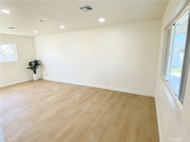 unfurnished room featuring light wood finished floors, plenty of natural light, and visible vents