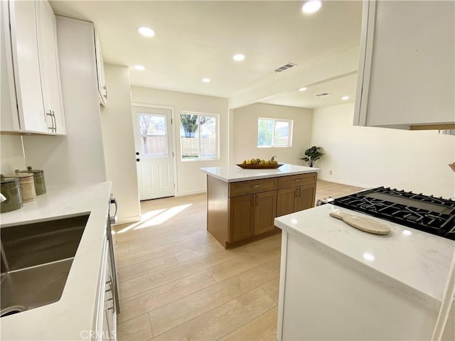 kitchen featuring white cabinetry, light wood-style floors, visible vents, light countertops, and a center island