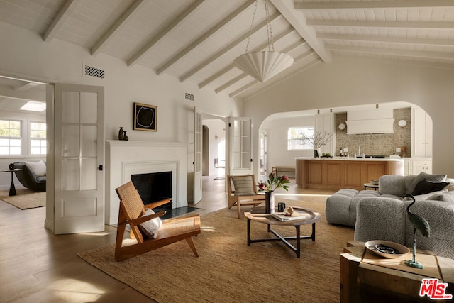 living room with beamed ceiling, high vaulted ceiling, and hardwood / wood-style floors