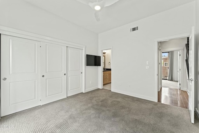 unfurnished bedroom featuring carpet floors, a closet, ceiling fan, and ensuite bathroom
