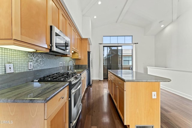 kitchen with dark wood-type flooring, appliances with stainless steel finishes, sink, and a kitchen island