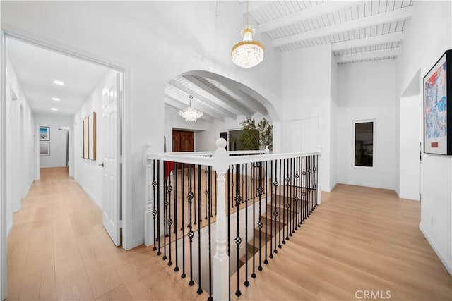 corridor with hardwood / wood-style floors, high vaulted ceiling, beamed ceiling, wood ceiling, and an inviting chandelier