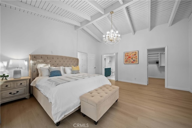 bedroom with an inviting chandelier, a spacious closet, beam ceiling, and light hardwood / wood-style flooring