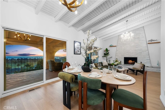 dining area featuring a fireplace, hardwood / wood-style flooring, a notable chandelier, wood ceiling, and beam ceiling