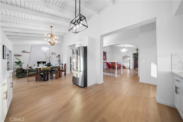 dining room featuring lofted ceiling with beams, a notable chandelier, wood ceiling, and light hardwood / wood-style flooring