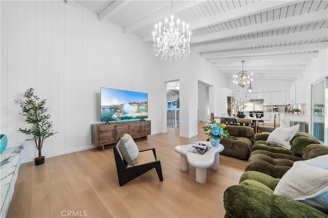 living room with an inviting chandelier, light hardwood / wood-style flooring, and vaulted ceiling with beams