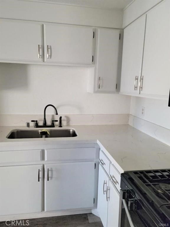 kitchen featuring gas range oven, sink, and white cabinets