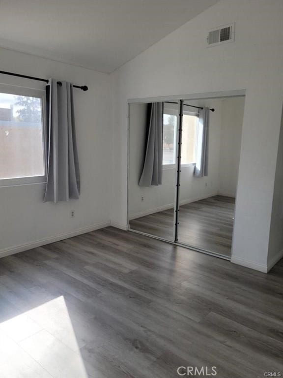 spare room with hardwood / wood-style flooring and vaulted ceiling