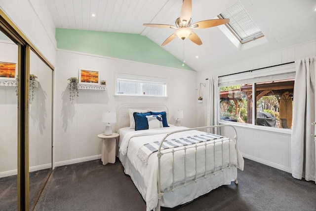 bedroom featuring ceiling fan, dark carpet, a closet, and vaulted ceiling with skylight