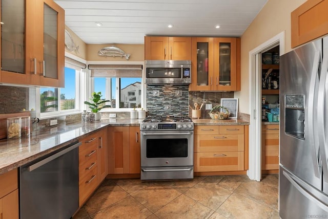 kitchen featuring appliances with stainless steel finishes, stone countertops, and decorative backsplash