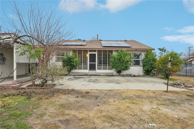 back of property featuring solar panels, fence, a sunroom, stucco siding, and a patio area