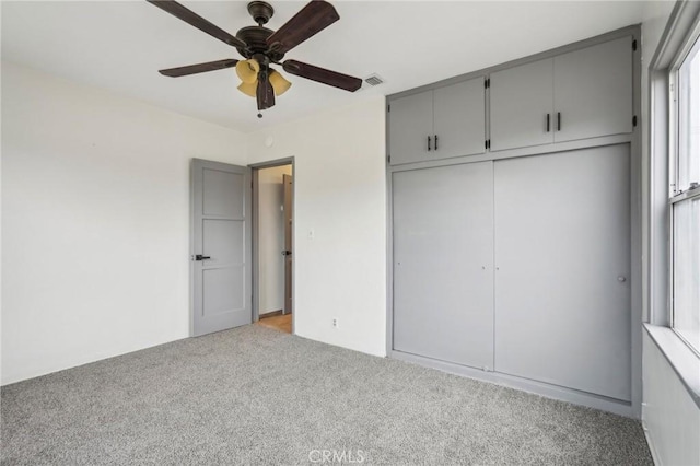 unfurnished bedroom with light carpet, a ceiling fan, visible vents, and a closet