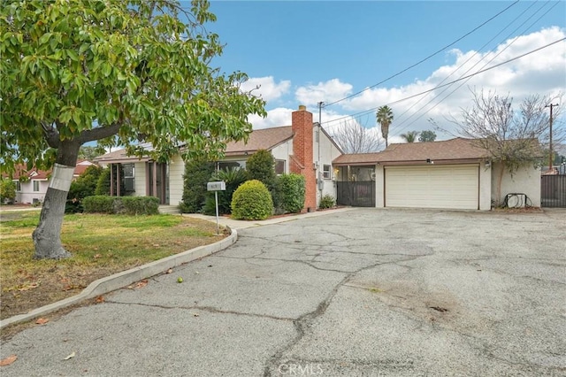 ranch-style house featuring a garage, fence, a front lawn, and aphalt driveway