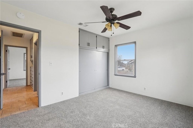 unfurnished bedroom with light carpet, a closet, visible vents, and a ceiling fan