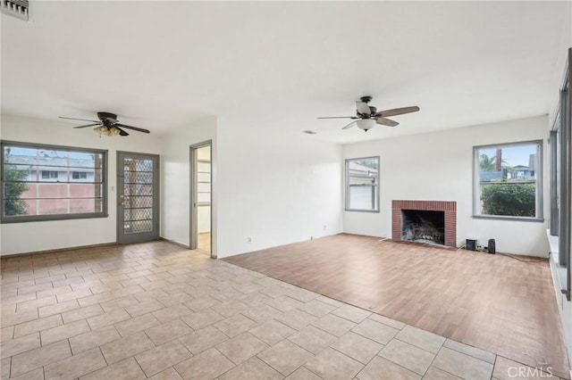 unfurnished living room with a wealth of natural light, visible vents, a fireplace, and light tile patterned flooring