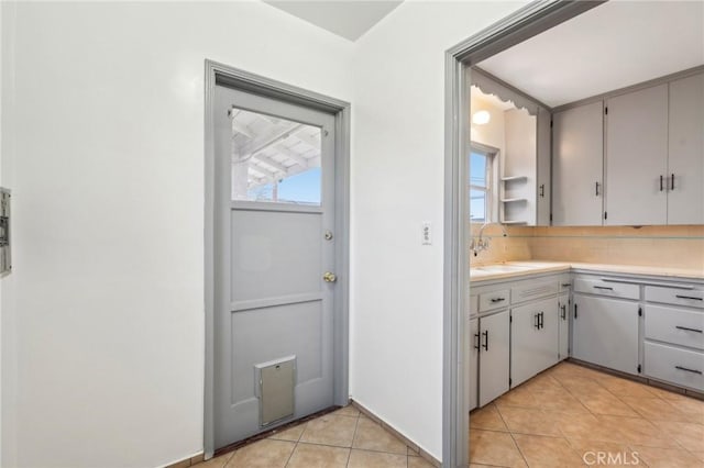 kitchen with light countertops, a sink, decorative backsplash, and light tile patterned floors