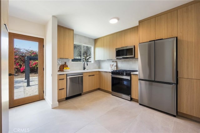 kitchen with appliances with stainless steel finishes, sink, light brown cabinetry, and backsplash