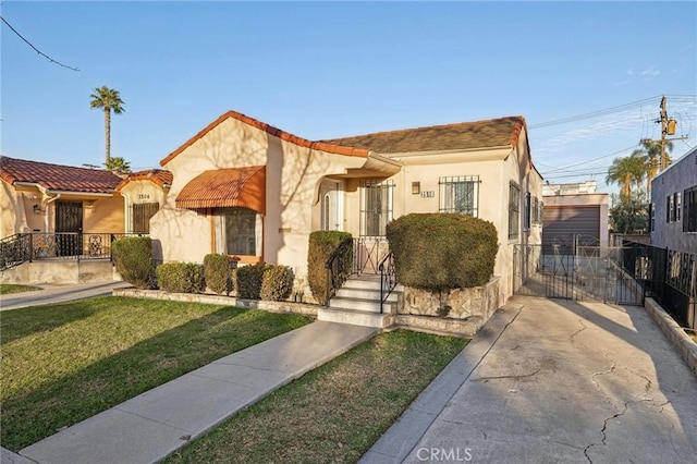 mediterranean / spanish-style house featuring a gate, fence, a front lawn, and stucco siding