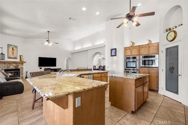 kitchen with a kitchen island with sink, oven, and ceiling fan