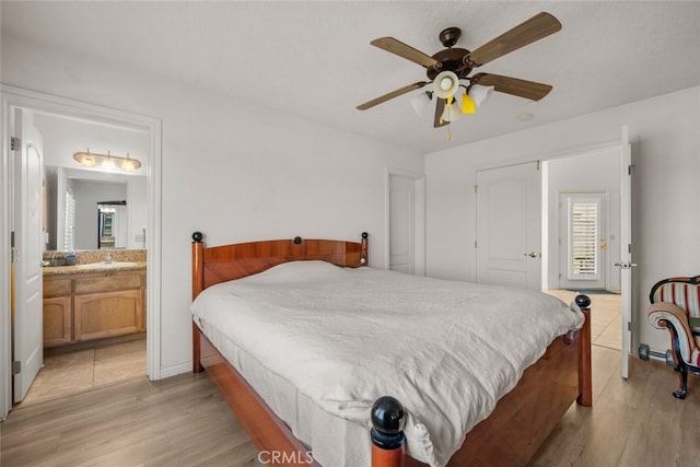 bedroom featuring ceiling fan, light hardwood / wood-style floors, and ensuite bath