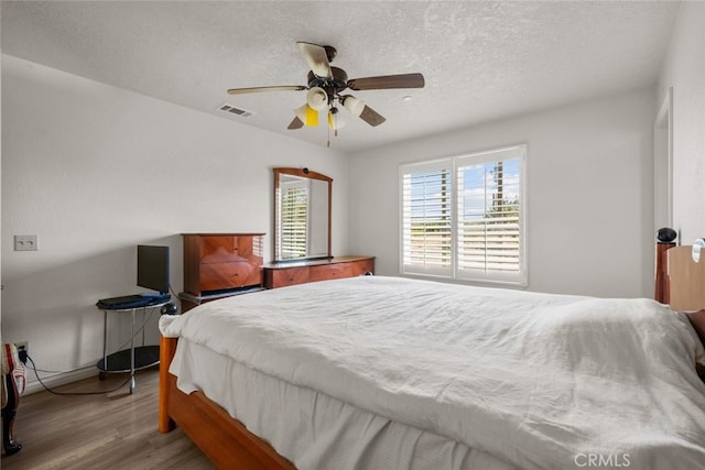 bedroom featuring ceiling fan, a textured ceiling, and light hardwood / wood-style flooring