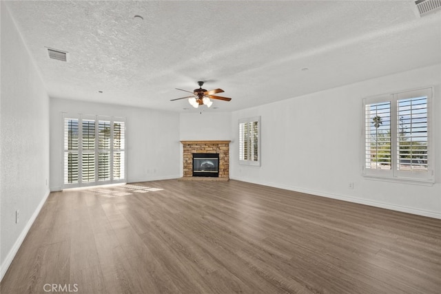 unfurnished living room featuring plenty of natural light, dark wood-type flooring, a textured ceiling, and ceiling fan