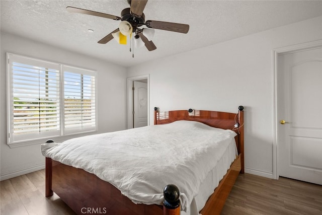 bedroom with ceiling fan, dark wood-type flooring, and a textured ceiling